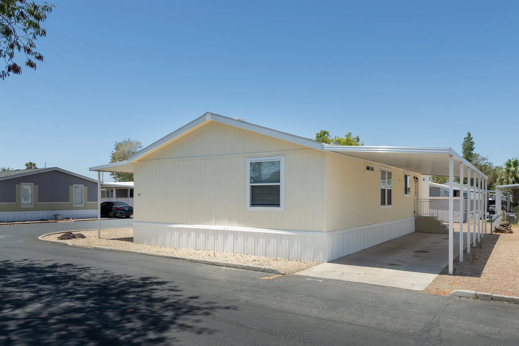 Home #70: cream double-wide with white trim, covered carport and corner lot